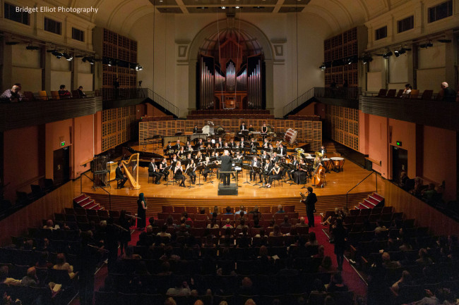 World Premiere of 'First Light at Uluru' for Wind Symphony with 25 extra players positioned throughout the audience.